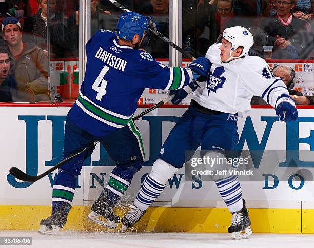 Nikolai Kulemin of the Toronto Maple Leafs gets checked into the boards by Rob Davison of the Vancouver Canucks during their game against the Toronto...