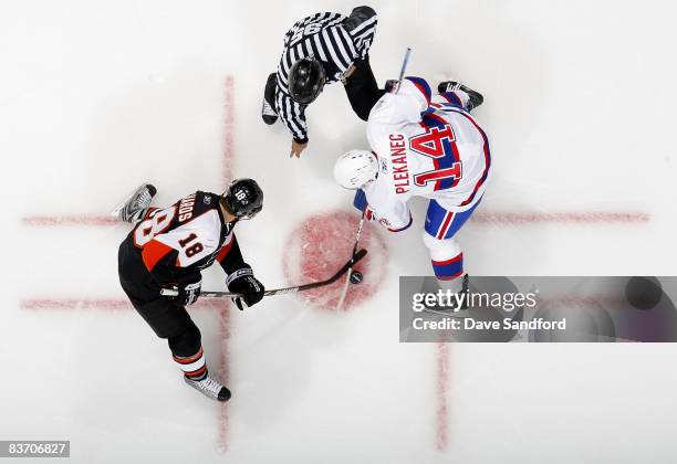 Tomas Plekanec of the Montreal Canadiens takes a face-off against Mike Richards of the Philadelphia Flyers as linesman Jonny Murray drops the puck...