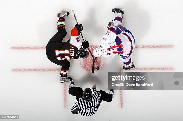 Saku Koivu of the Montreal Canadiens takes a face-off against Glen Metropolit of the Philadelphia Flyers as linesman Jonny Murray drops the puck...