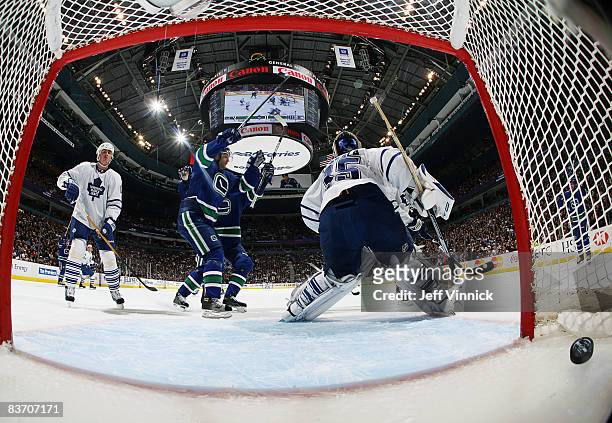 Pavol Demitra of the Vancouver Canucks celebrates a goal by teammate Daniel Sedin while Tomas Kaberle of the Toronto Maple Leafs looks on dejected...