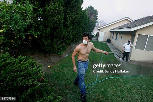 Seth Leavitt hoses his backyard November 15, 2008 in Yorba Linda, California. Strong Santa Ana winds are fanning flames throughout Southern...