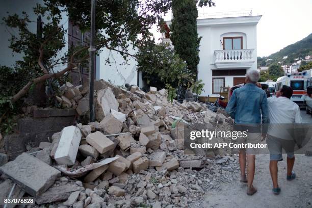 People walk next to collapsed houses in Casamicciola Terme, on the Italian island of Ischia, on August 22 after an earthquake hit the popular Italian...