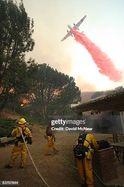 Firefighting airtanker drops Phos-Check fire retardant over firefighters trying to protect a house from the Corona Fire on November 15, 2008 in Yorba...