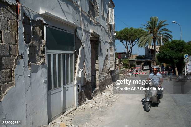 Policeman rides a scooter next to a damaged house in Casamicciola Terme, on the Italian island of Ischia, on August 22 after an earthquake hit the...