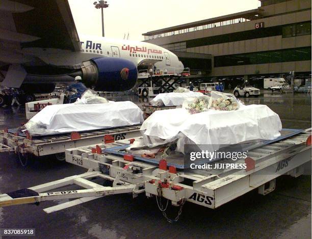 Covered with white palls, 10 coffins of the Japanese victims from the Luxor massacre are unloaded from the airplane after returning from Egypt with...