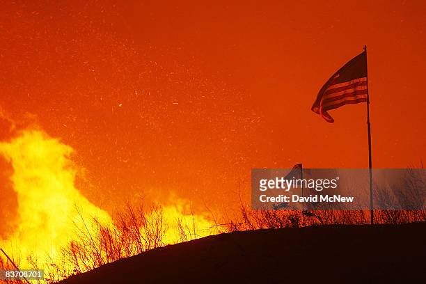 An American flag flies on a hill as fire draws close to homes on November 15, 2008 in Yorba Linda, California. Strong Santa Ana Winds are destroying...