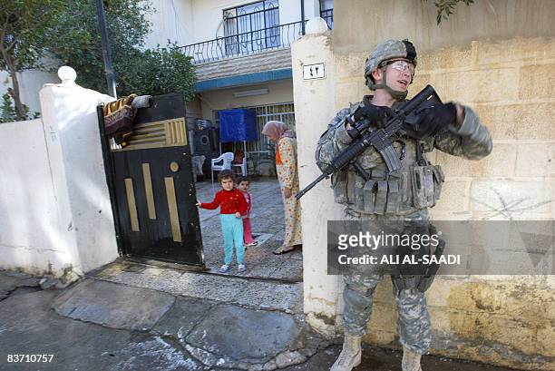 An Iraqi girl stands at the gate of their courtyard as she watches an US soldier, member of a patrol, pass by in the northern city of Mosul, some 370...