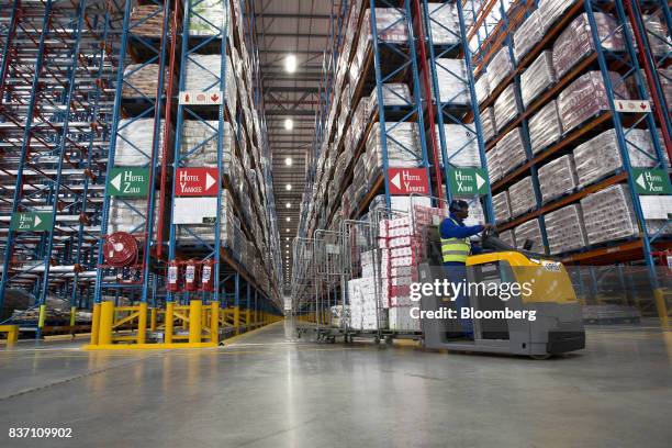 Worker collects food products from storage aisles using an electric cart at Shoprite Holdings Ltd.'s new Cilmore distribution center in Cape Town,...