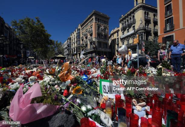 People display flowers and candles to pay tribute to the victims of the Barcelona and Cambrils attacks on the Rambla boulevard in Barcelona on August...