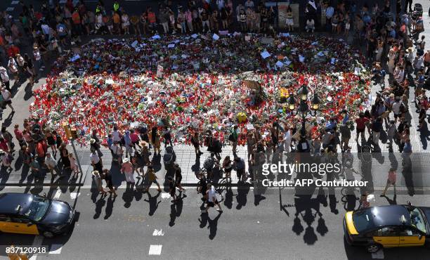 People display flowers and candles to pay tribute to the victims of the Barcelona and Cambrils attacks on the Rambla boulevard in Barcelona on August...