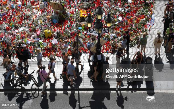 People display flowers and candles to pay tribute to the victims of the Barcelona and Cambrils attacks on the Rambla boulevard in Barcelona on August...