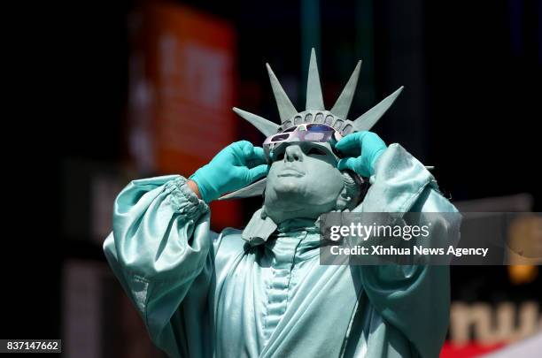 Aug. 21, 2017 -- A man cosplaying the Statue of Liberty watches a partial solar eclipse in New York, the United States, on Aug. 21, 2017. A...