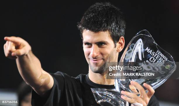 Novak Djokovic of Serbia points to his girlfriend in the stands as he holds the winner's trophy following his victory over Nikolay Davydenko of...