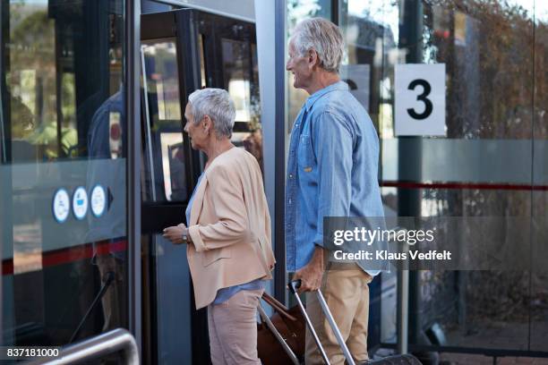 senior couple, waiting for a bus, at public transport station - airport couple stockfoto's en -beelden