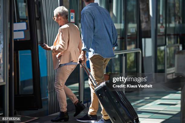 senior couple walking into bus, from public transport platform - boarding a bus stock-fotos und bilder