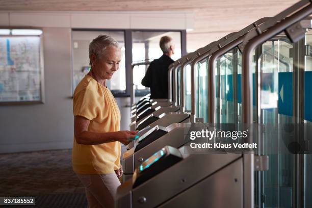 senior woman checking out at metro station - drehkreuz stock-fotos und bilder