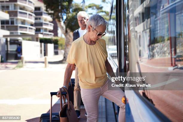 senior couple walking on to public bus - boarding a bus stock-fotos und bilder