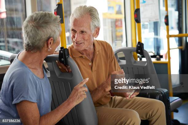 senior couple talking together on public bus and holding smartphone - man riding bus fotografías e imágenes de stock