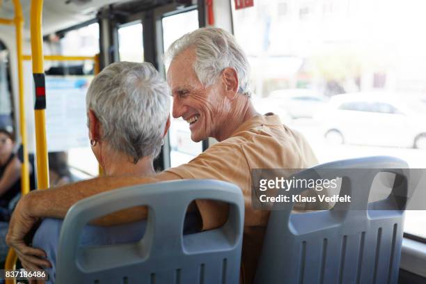 senior couple with arms around each other, riding with public bus - white hair stock-fotos und bilder