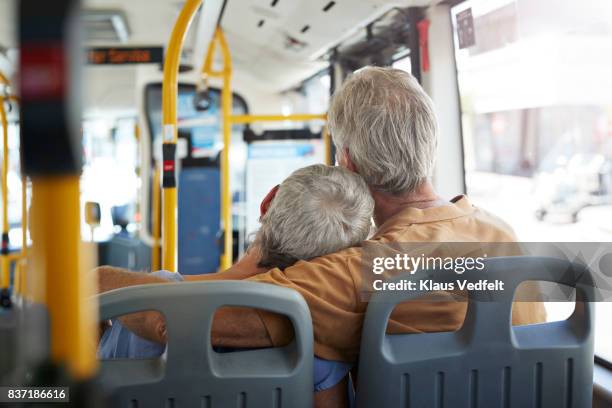 senior couple with arms around each other, riding with public bus - öffentliches verkehrsmittel stock-fotos und bilder