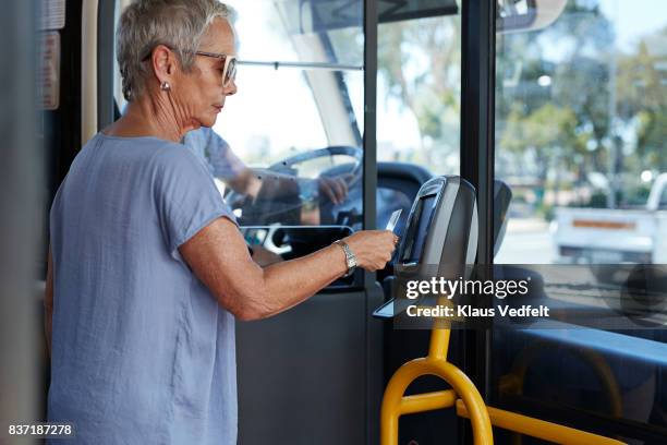 mature woman using travel card to pay for public bus ride - contactless payment bus stock pictures, royalty-free photos & images