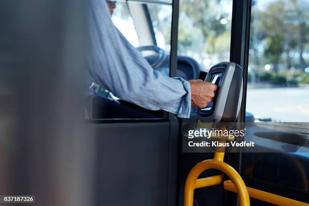 mature man using travel card to pay for public bus ride - transporte público fotografías e imágenes de stock