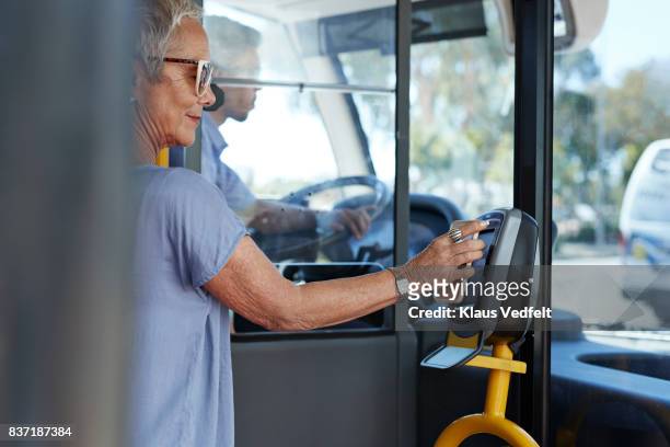 mature woman using smartphone to pay for public bus ride - public transport ストックフォトと画像