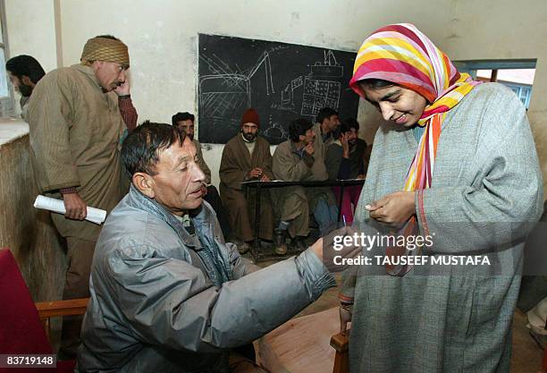 An election official marks the finger of a voter with indelible ink prior to casting his vote at a polling station in Bandipora south of Srinagar on...