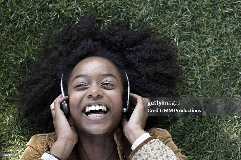Woman listening to music lying on grass