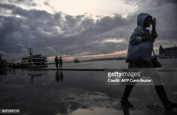 People walk near the port of Kadikoy at sunset on August 22, 2017 in Istanbul. / AFP PHOTO / BULENT KILIC