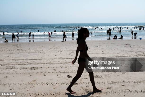 Woman walks along Rockaway Beach on a hot summer day on August 22, 2017 in the Queens borough of New York City. New York and much of the Northeast is...