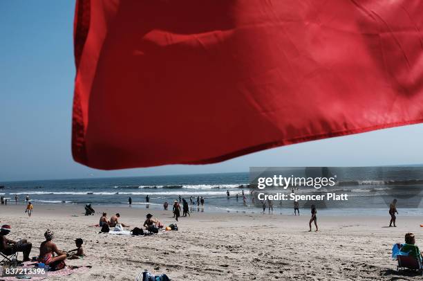Red warning flag flaps in the wind along Rockaway Beach as visitors try to stay cool on a hot summer day on August 22, 2017 in the Queens borough of...