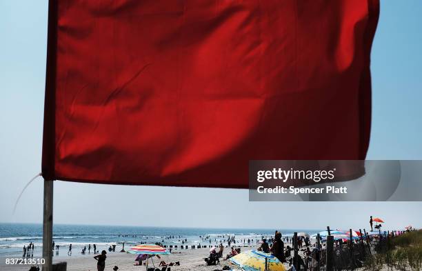 Red warning flag flaps in the wind along Rockaway Beach as visitors try to stay cool on a hot summer day on August 22, 2017 in the Queens borough of...