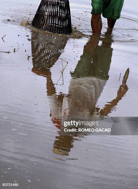 Filipino farmer Generoso Hesuna catches mudfish using a bamboo trap in a pool of water at a farm planted with rice and sugar in Santa Catalina town...