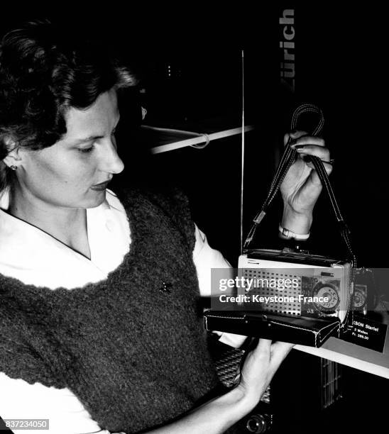 Une jeune femme tient une radio miniature qui tiendrait dans un sac à main lors d'une exposition à Zurich, Suisse.