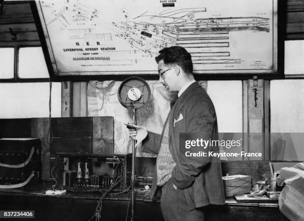 Un homme annonce au haut-parleur les arrivées et départs des trains de la gare londonienne Liverpool Street à Londres, Royaume-Uni.