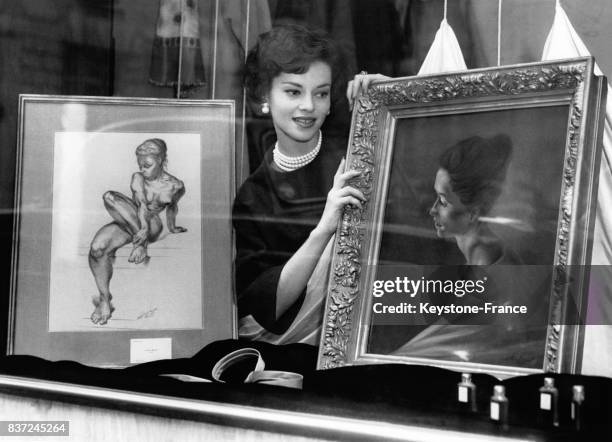 Le modèle Svetlana Kassinova observe le portrait d'elle qu'a réalisé le peintre Tony Brandt et qu'un coiffeur anglais amateur d'art a exposé dans la...