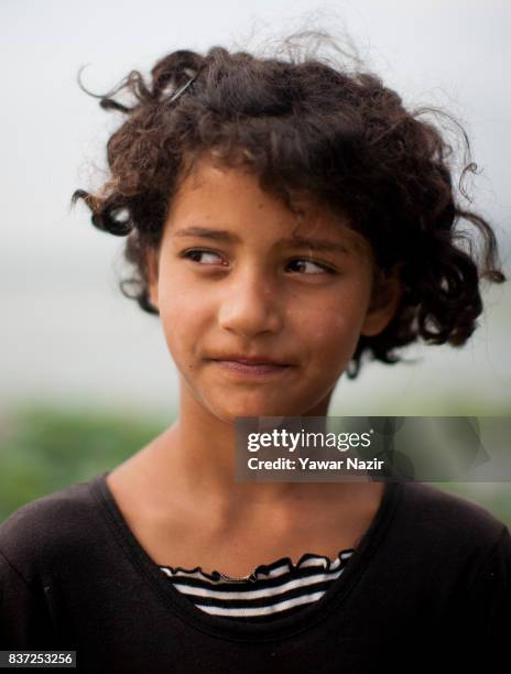 Kashmiri girl look towards the floating lotus garden in Dal lake on August 22, 2017 in Srinagar, the summer capital of Indian administered Kashmir,...