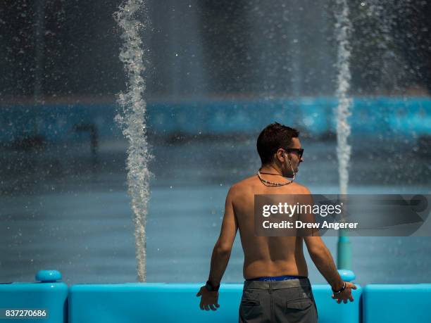 Man cools off in the fountains at Flushing Meadows-Corona Park, August 22, 2017 in the Queens borough of New York City. With heat index values near...