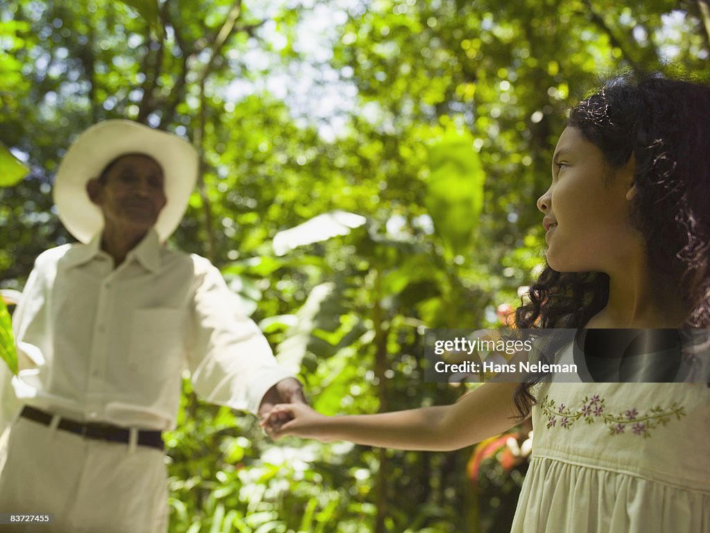 Granddaughter walking with grandfather in garden