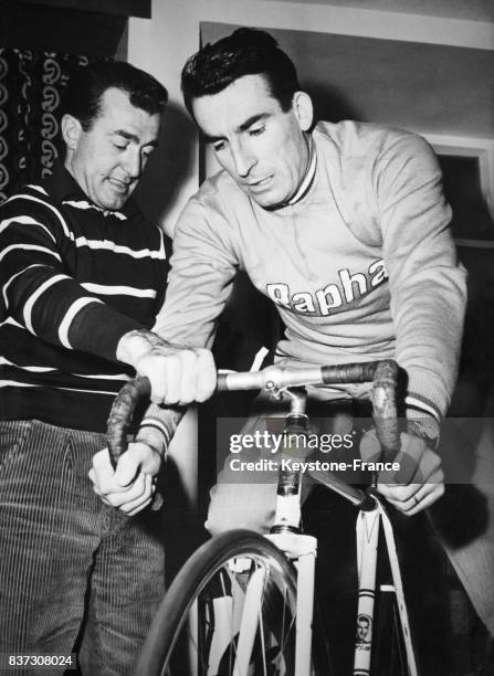 Louison Bobet encourageant son ami Raphaël Géminiani, convalescent, qui fait du home-trainer dans sa maison à Clermont-Ferrand, France, le 24 janvier...