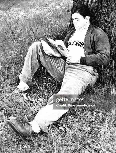 Le boxeur américain Jimmy Braddock lit 'Des Souris et des hommes' de Steinbeck au pied d'un arbre lors d'une pause détente au cours de son...