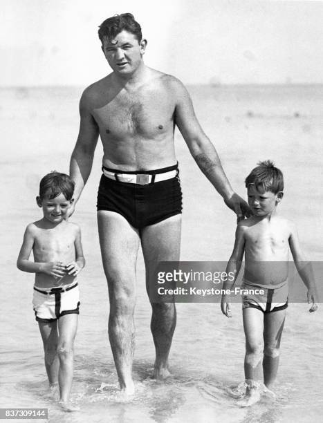 Le boxeur Jimmy Braddock en vacances au bord de la mer sort de l'eau avec ses deux jeunes fils Jim Junior et Howard le 12 mars 1936 à Miami, FL.