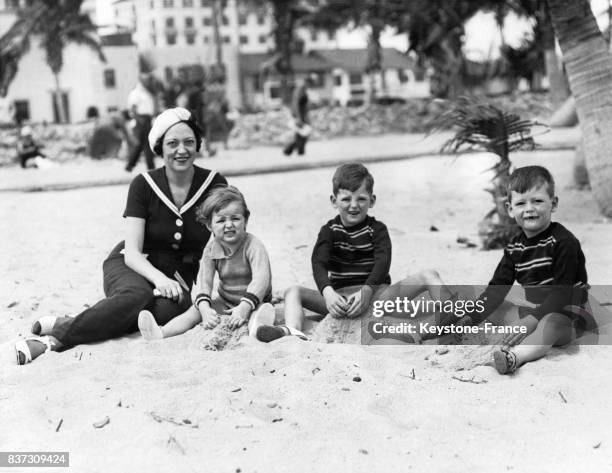 Mae Braddock, femme du boxeur américain Jimmy Braddock, avec trois de leurs enfants Rosemarie, Jim Jr et Howard sur la plage au bord de la mer le 25...