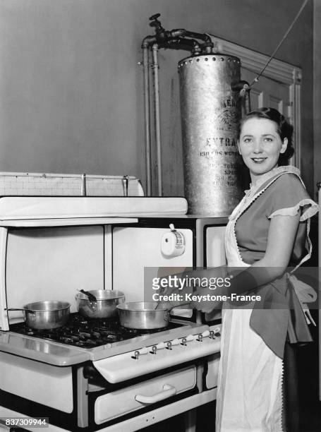 Le mannequin Marie Bard pose avec un tablier affairée à ses casseroles sur la cuisinière dans le cadre d'une publicité pour des ustensiles de cuisine...