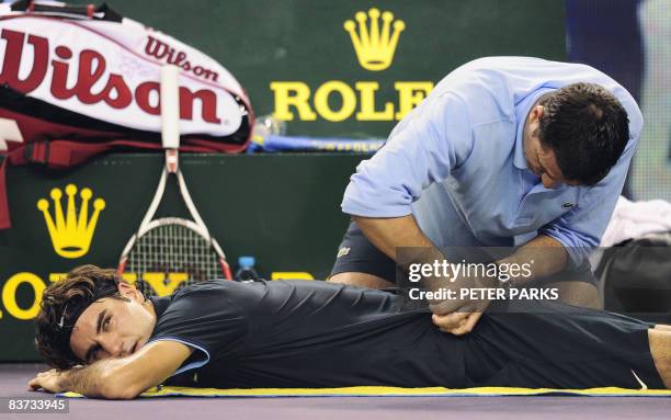 Trainer works on the back of Roger Federer of Switzerland during a break while playing Andy Murray of Britain in their men's singles match on the...