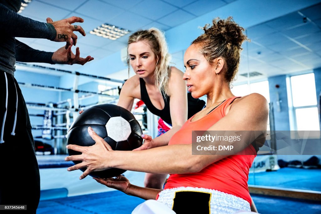 Two woman exercising using medicine ball