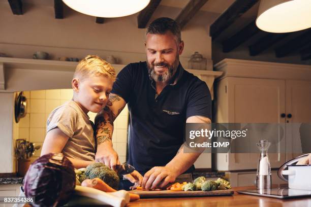 man teaching how to cut vegetables to his son - chopped stock pictures, royalty-free photos & images