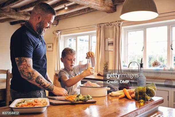 father and son cooking lunch in kitchen - roast dinner stock pictures, royalty-free photos & images