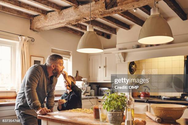 father and son eating pizza in kitchen at home - cooking tasting stock pictures, royalty-free photos & images